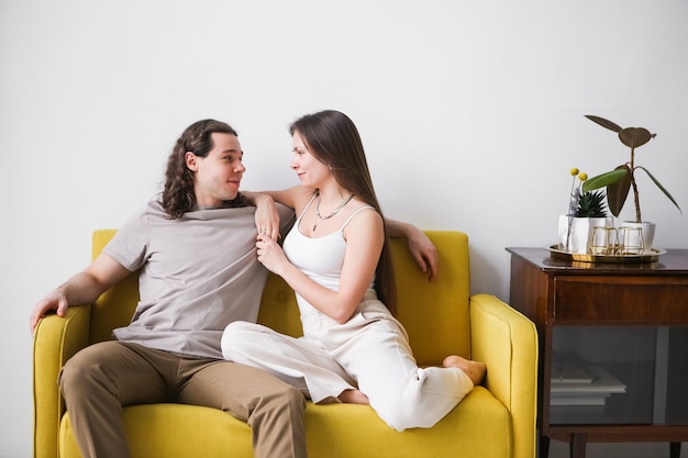 Photo couple sitting on yellow sofa in the room man and woman in love in a new apartment home comfort