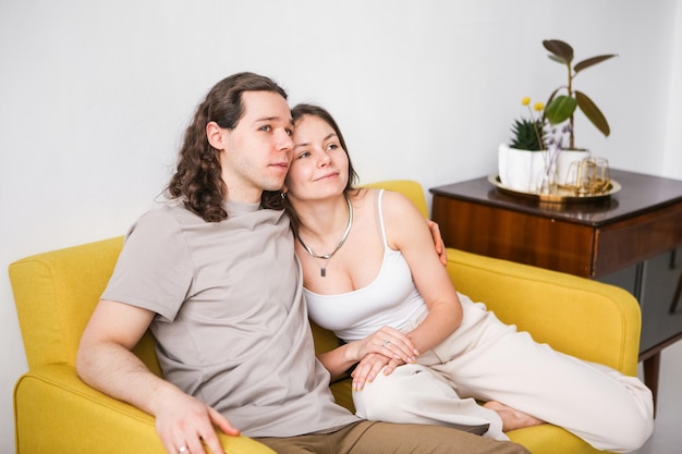 Photo couple sitting on yellow sofa in the room man and woman in love in a new apartment home comfort