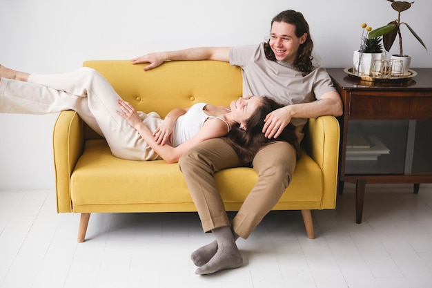 Couple sitting on yellow sofa in the room Man and woman in love in a new apartment Home comfort