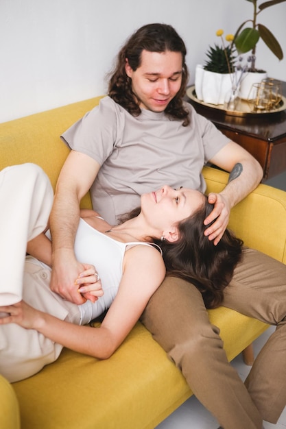 Foto coppia seduta sul divano giallo nella stanza uomo e donna innamorati in un nuovo appartamento comfort domestico