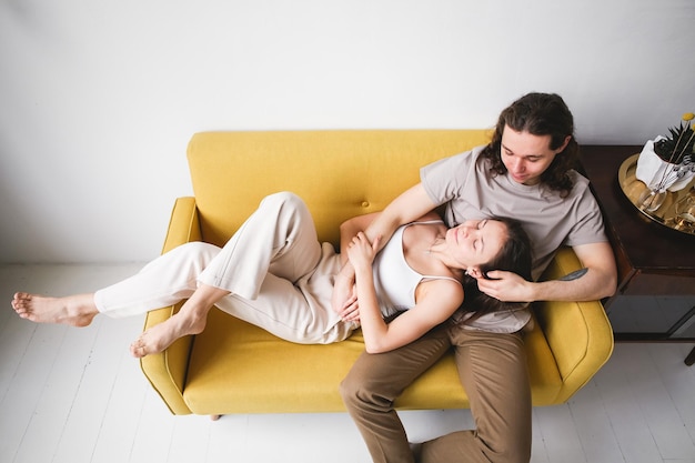 Photo couple sitting on yellow sofa in the room man and woman in love in a new apartment home comfort