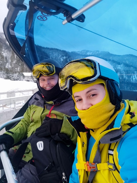 Пара лыжников и сноубордистов на кресельном подъемнике