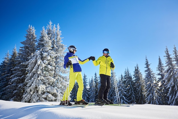 Couple of skiers on skis on hill at ski resort Recreational activities in mountains concept