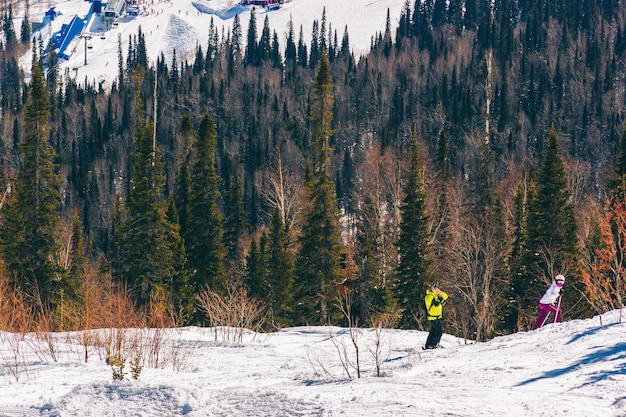 A couple skiing and taking pictures on the slope of a ski resort