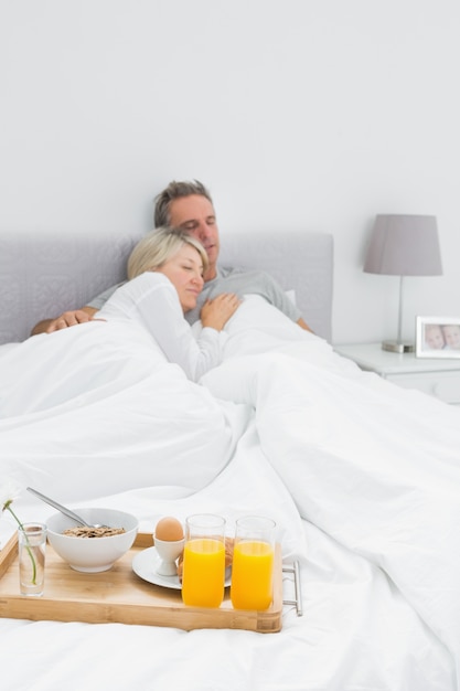 Couple sleeping with breakfast tray at end of bed