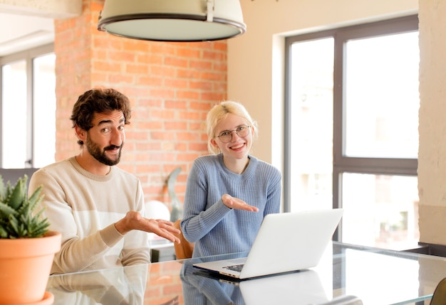 couple smiling cheerfully, woman feeling happy and showing a concept in copy space with palm of hand