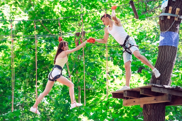 Couple spend their leisure time in a ropes course. man and woman engaged in rock-climbing,