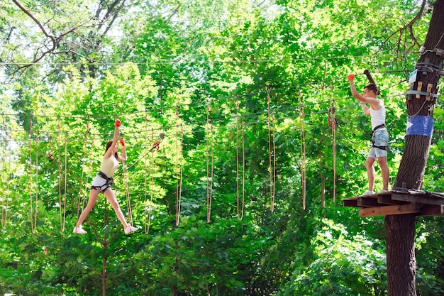 Couple spend their leisure time in a ropes course. man and woman engaged in rock-climbing, 