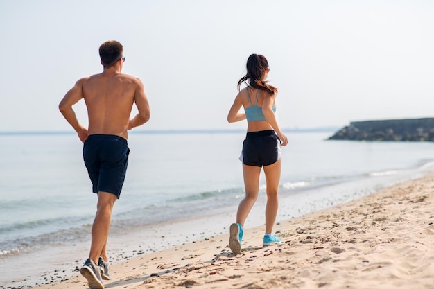 스포츠 옷 을 입은 부부 가 해변 에서 달리고 있다