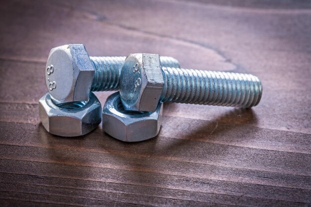 Couple of stainless bolt details and nuts on vintage brown wooden board maintenance concept