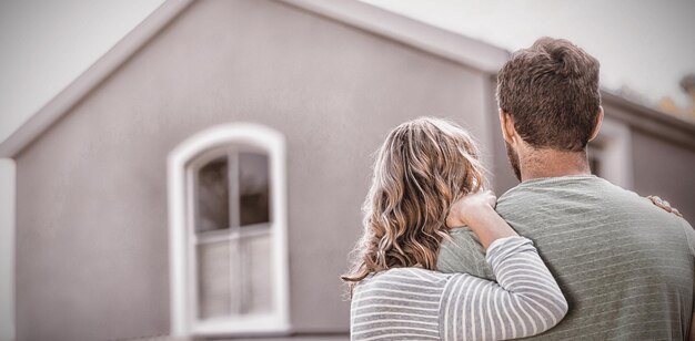 Couple standing against house