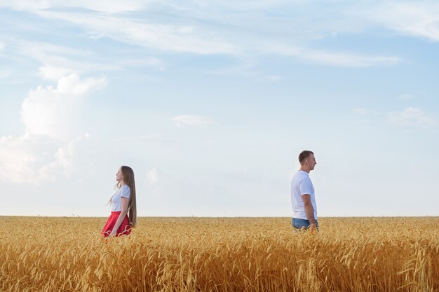 Couple standing back to each other in wheat field. Divorce