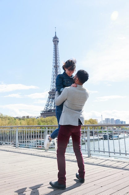 couple standing on bridge against eiffel tower