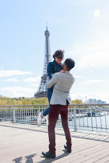 Foto la coppia in piedi sul ponte contro la torre eiffel