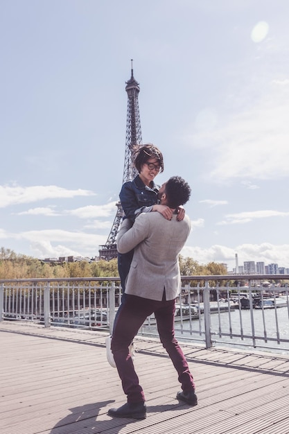 Foto la coppia in piedi sul ponte contro la torre eiffel