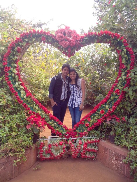 Photo couple standing in flower arrangement of heart