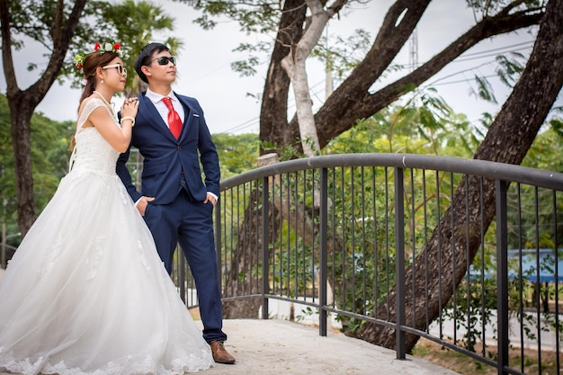 Couple standing on footbridge against trees