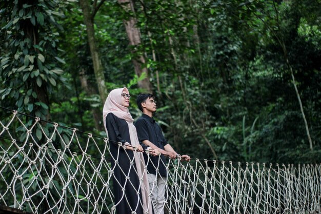 Photo couple standing on footbridge in forest