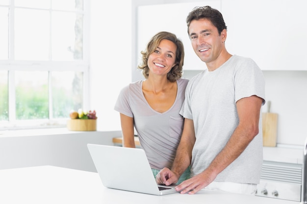 Couple standing in kitchen with laptop