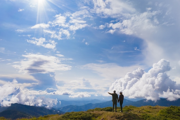 The couple standing on a mountain against beautiful clouds