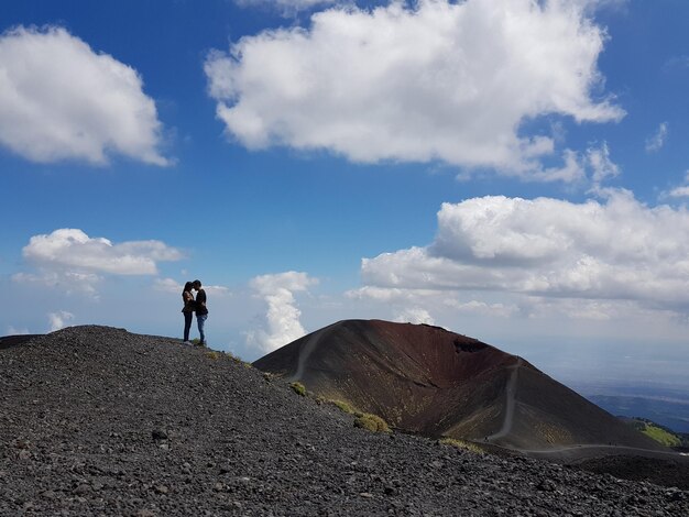 Foto la coppia in piedi sulla montagna contro il cielo