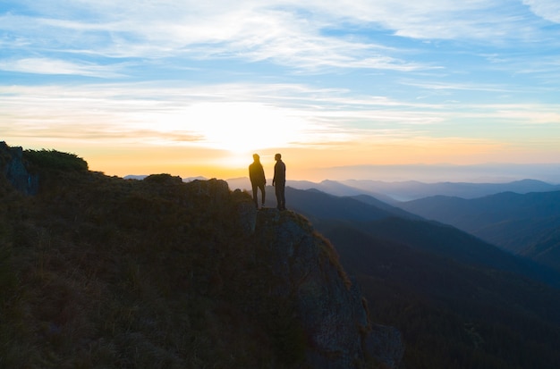The couple standing on the mountain on the sunrise background
