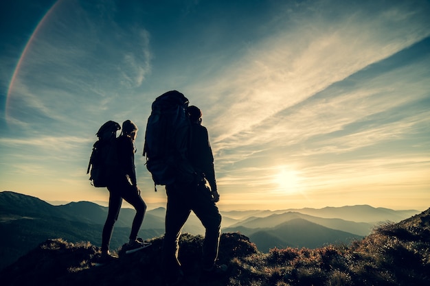 The couple standing on a mountain with a picturesque sunrise background