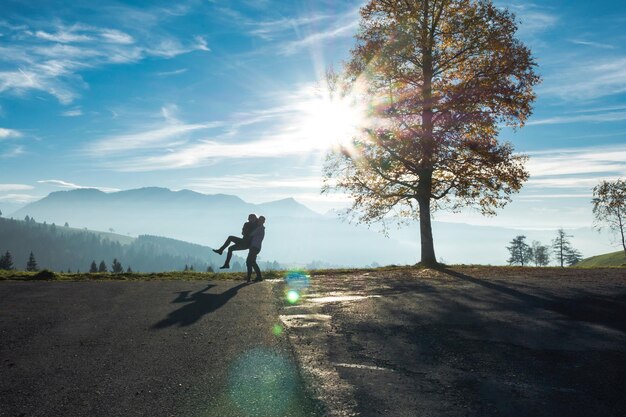 写真 夕暮れの空に照らされた道路に立っているカップル