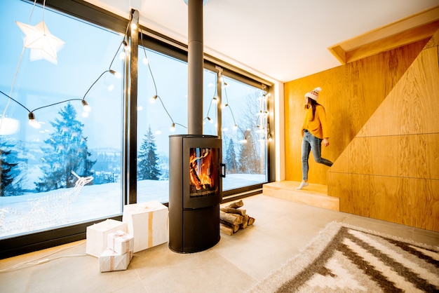 Couple standing outdoors on the terrace of the house with fireplace during the winter time. Interior view through the window