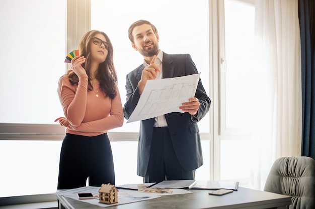 Couple standing in room and holding blueprint