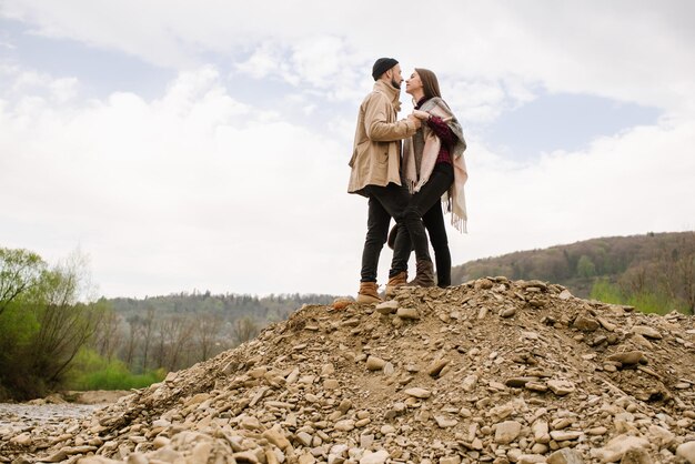 A couple standing together on the rocky hill against the sky