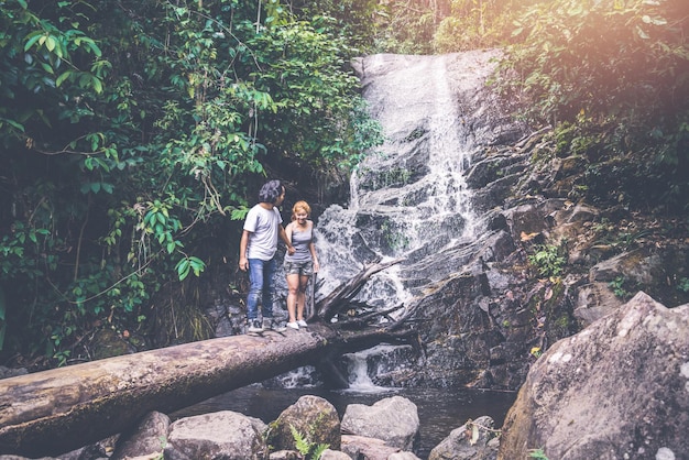 Photo couple standing in tree trunk against waterfall