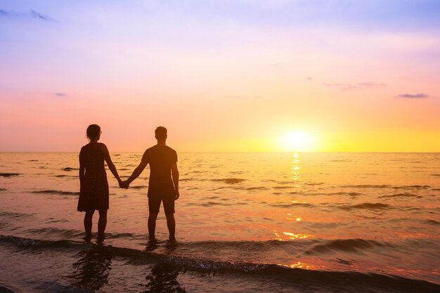 Couple standing in the water at sunset