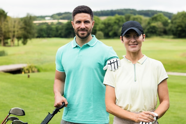 couple standing with golf club and bag in golf course