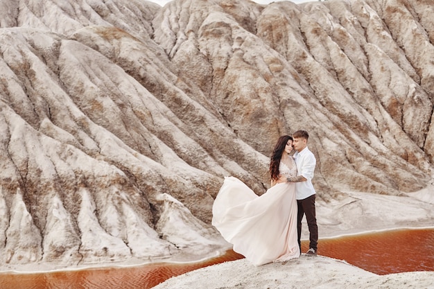 Couple stands on the precipice of the mountain and the red lake