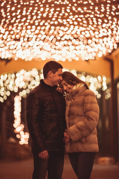 Couple at the street before Christmas time. Bokeh lights decorations backdrop