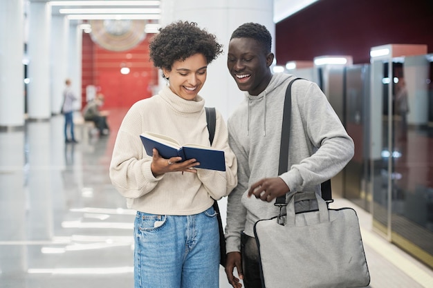 Couple of students discussing a new book standing in the subway