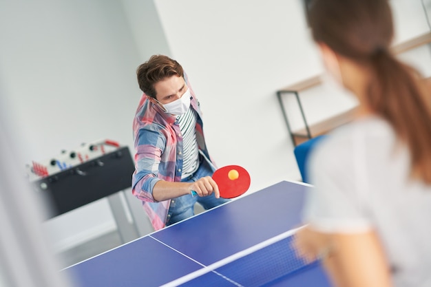 Coppia di studenti che indossano maschere mentre giocano a ping pong nel campus