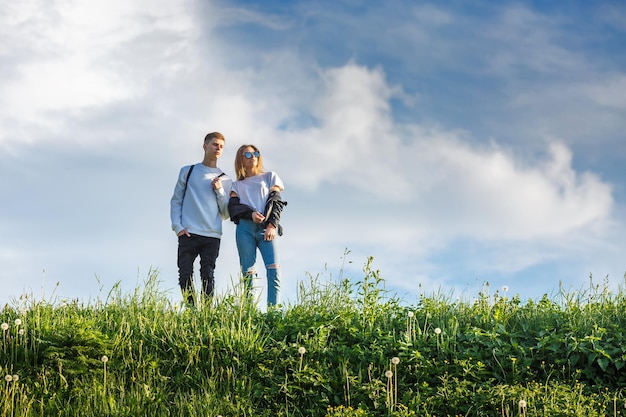 Couple of stylish teenagers on a high mountain against the sky look into the future concept