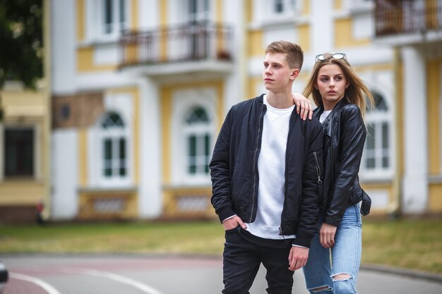 Couple of stylish teenagers on street against old building look into the future concept
