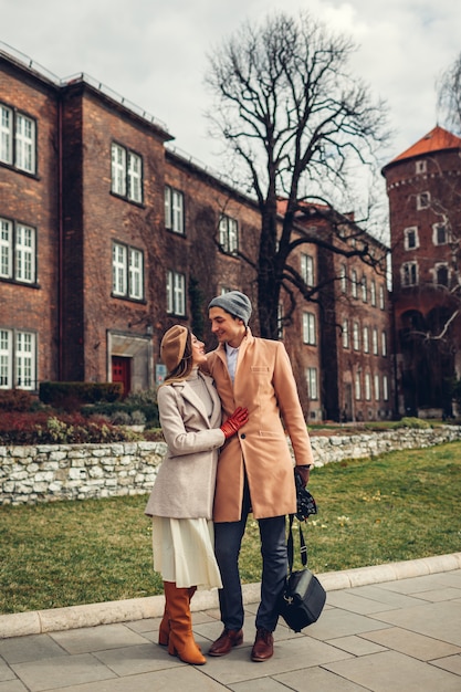 Couple of stylish tourists walking hugging enjoying architecture of Wawel Castle in Krakow, Poland.