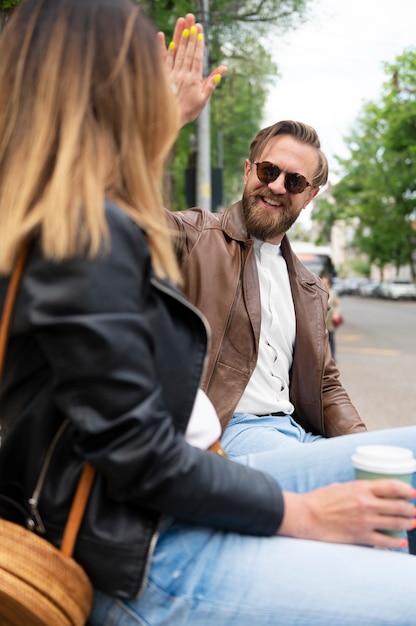 Photo couple in synthetic leather jackets high-fiving each other while having coffee