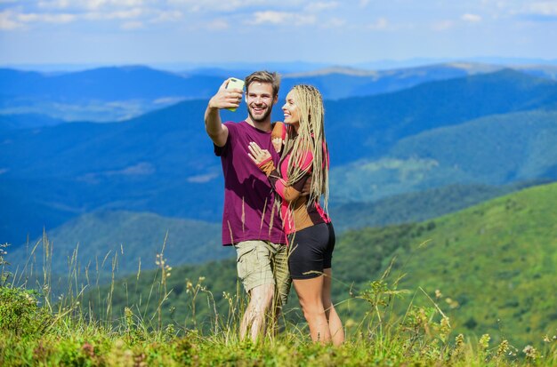 写真を撮るカップル 夏休みのコンセプト 若い冒険家 ダーリンと一緒に旅行 山をハイキングする愛のカップル 写真を撮ろう 美しさを捉える 男と女の携帯写真のポーズ