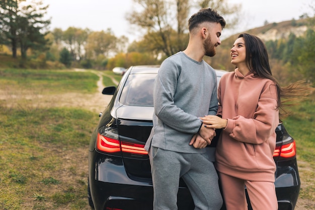 Couple talking leaning on car