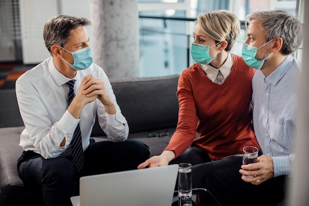 Couple talking to their agent while using laptop and wearing face masks on a meeting