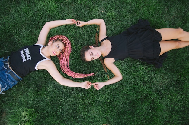 Couple of teen friends holding hands on the grass