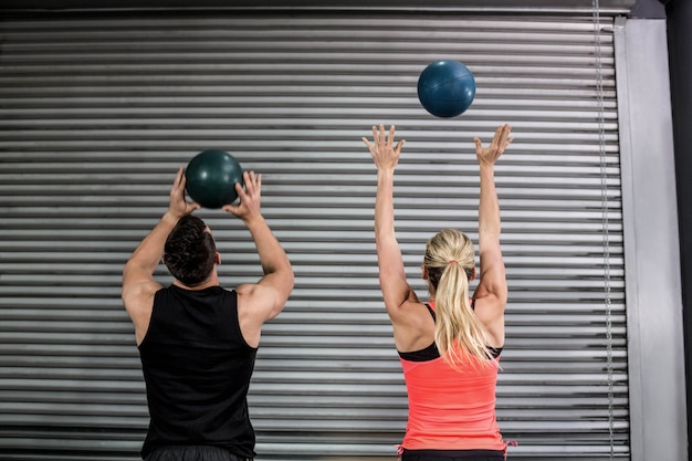 Couple throwing ball in the air at  gym