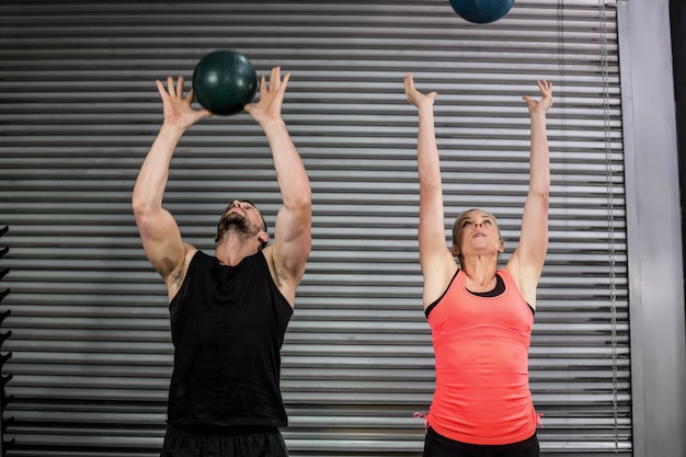 Couple throwing ball in the air at  gym