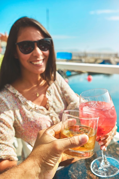 マリーナで夏の始まりを乾杯するカップルは、カップとガラスの夏のコンセプトを乾杯します