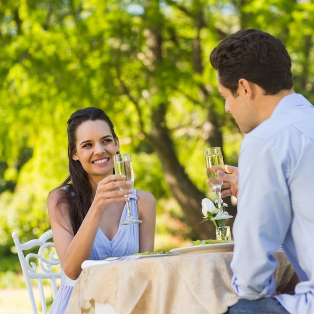 Couple toasting champagne flutes at an outdoor cafÃ©